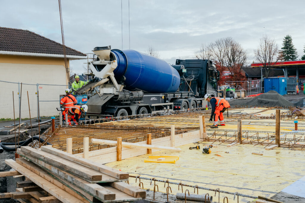 Arbeidere i verneutstyr ved betongbil under støping av armert dekke på byggeplass hos Ecosør