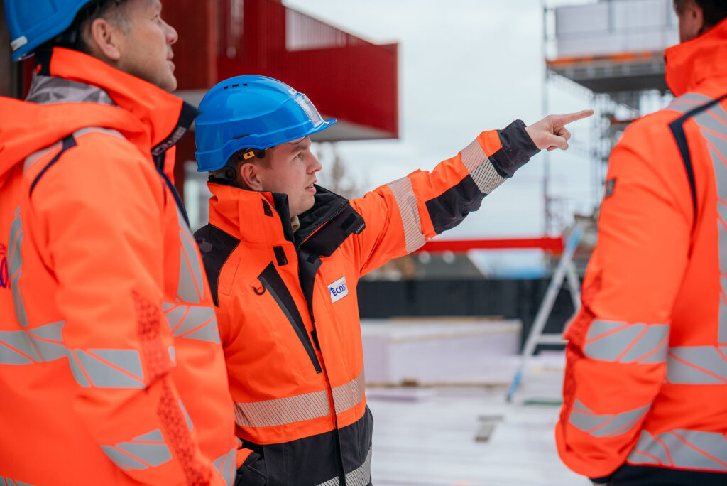 Ansatte i verneutstyr diskuterer arbeid på byggeplass hos Ecosør